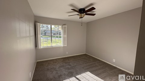 A room with a ceiling fan and a window letting in natural light.