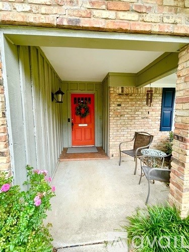 A red door with a wreath is on the left side of a covered walkway.