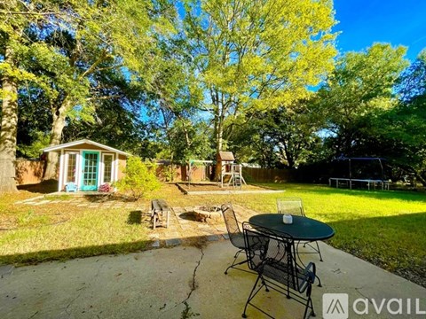 A patio with a table and chairs is surrounded by trees.