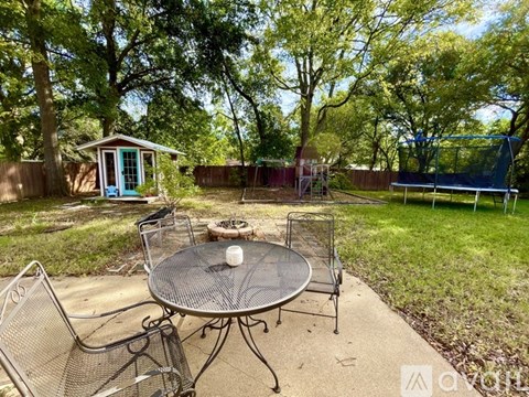 A backyard with a table and chairs and a shed.