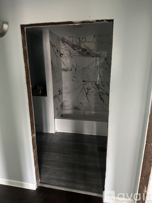 A bathroom with a marble wall and a bathtub.
