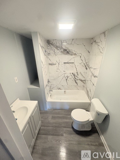 A room with dark wood flooring and two windows.