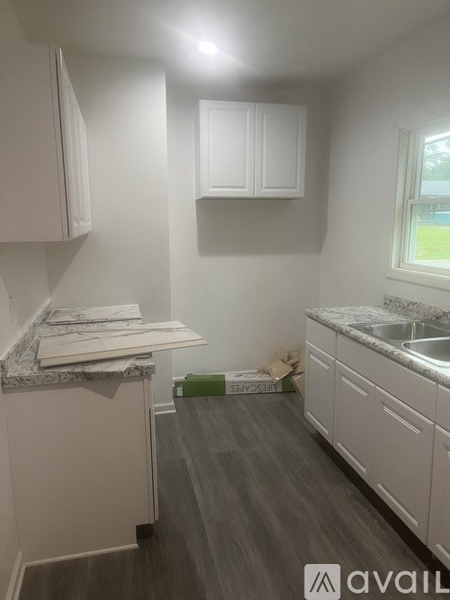 A kitchen with white cabinets and a marble countertop.