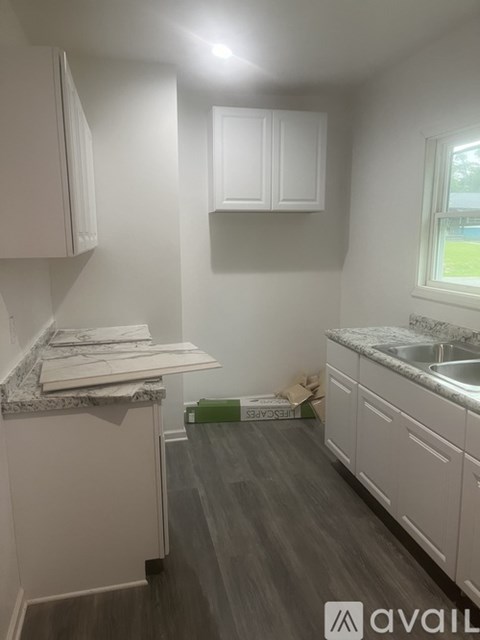 A kitchen with white cabinets and a marble countertop.