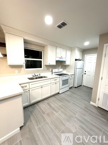 A kitchen with white cabinets and a grey floor.