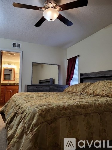A bedroom with a bed, dresser, mirror, and a ceiling fan.