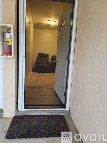 A doorway with a rug on the floor leading to a room with a chair.