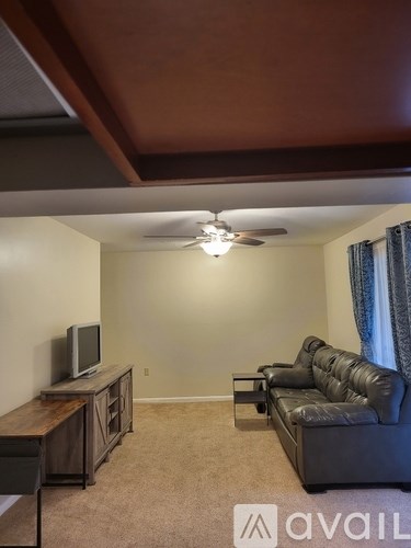 A living room with a couch, television, and a ceiling fan.