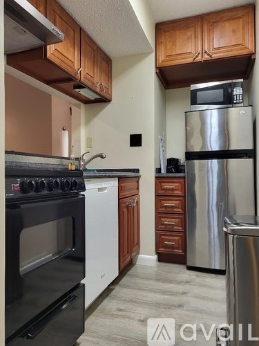 A kitchen with wooden cabinets and a stainless steel refrigerator.