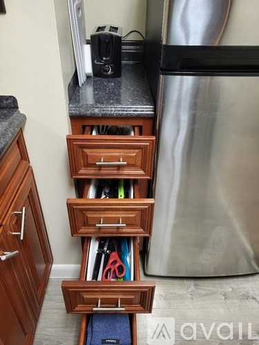 A kitchen with a stainless steel refrigerator and wooden drawers.