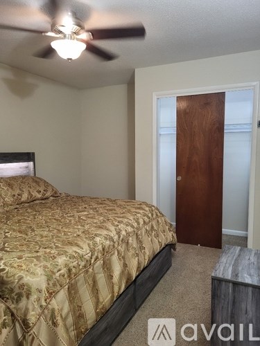 A bedroom with a bed, a ceiling fan, and a wooden door.