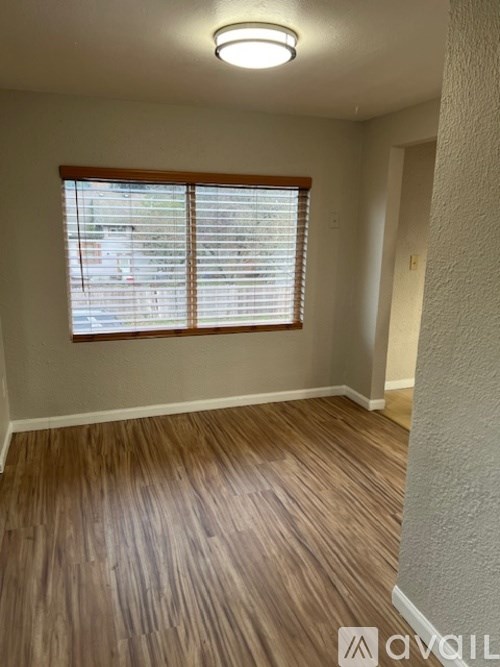 A room with wooden flooring and a window with blinds.
