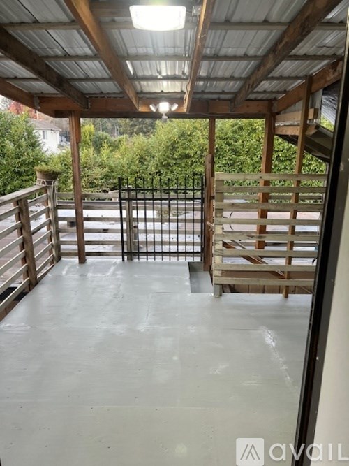 A patio with a metal railing and wooden steps leading to a backyard.