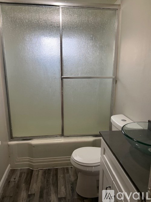 A bathroom with a glass shower door and a toilet.