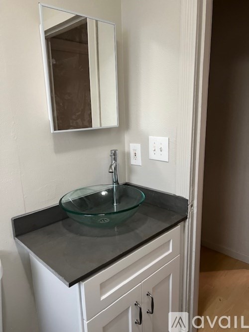 A bathroom vanity with a glass bowl sink and a mirror above it.