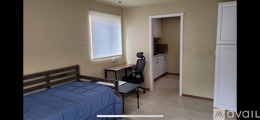 A bedroom with a bed, desk, and chair.