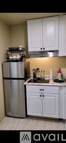 A kitchen with a stainless steel refrigerator and white cabinets.