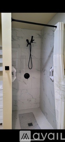 A bathroom with a shower curtain and a drain in the floor.