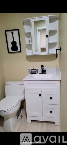 A bathroom with a toilet, sink, and a guitar picture on the wall.