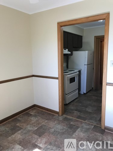 A kitchen with a white fridge and a wooden door.