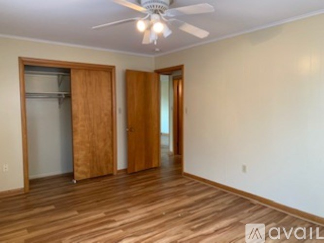 A room with a ceiling fan and wooden floors.