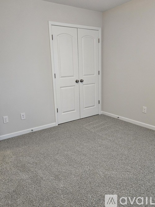 A white door is in a room with a carpeted floor.
