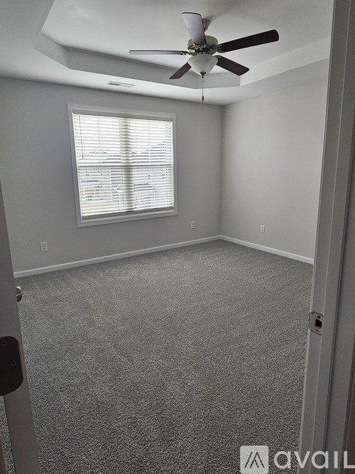 A room with a ceiling fan and a window with blinds.