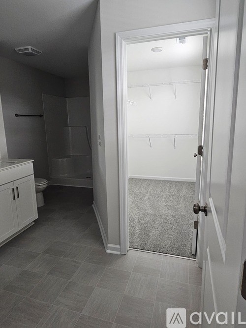 A white door is open to a room with a tiled floor and a walk-in closet with shelves.