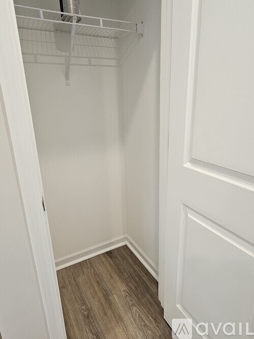 A white closet with a shelf and a door.