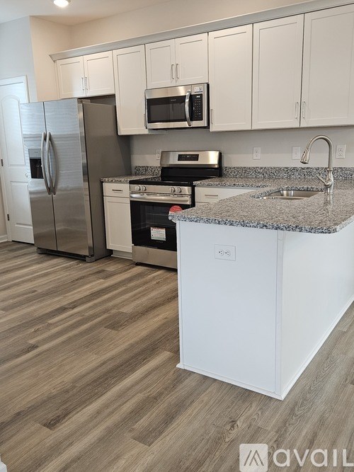 A kitchen with a refrigerator, microwave, oven, and sink.