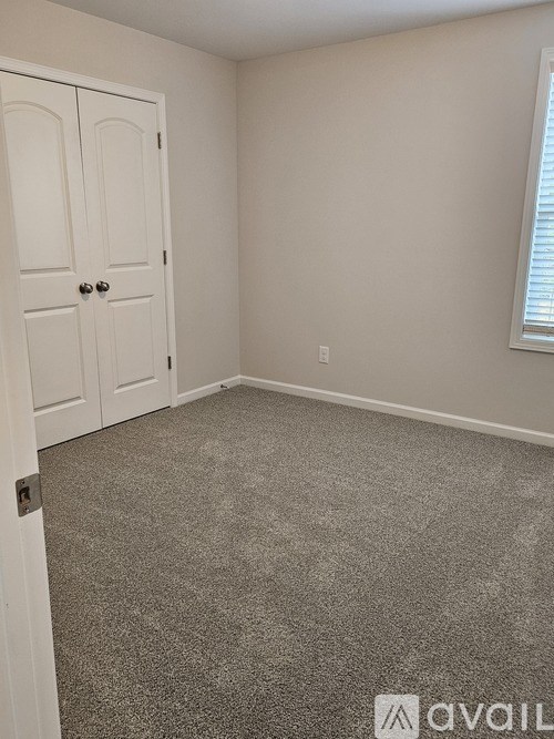 A room with a carpeted floor and a white door.