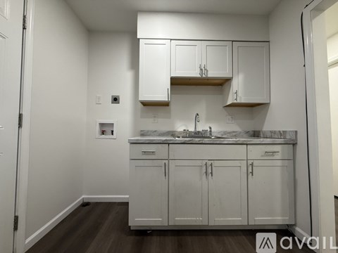 A kitchen with white cabinets and a marble countertop.