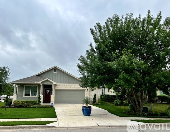 A house with a grey roof and a red door is surrounded by greenery.