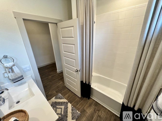 A bathroom with a white sink, a white door, and a white tiled wall.