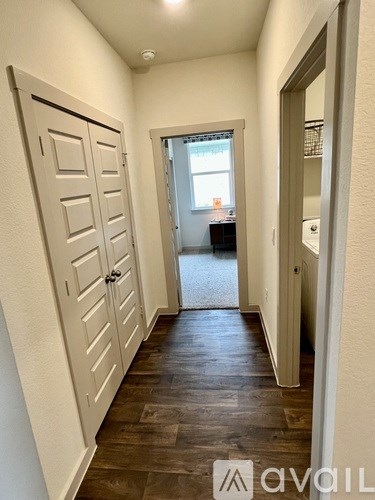A hallway with a wooden floor and white walls.