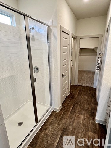 A bathroom with a walk-in shower and a wooden floor.