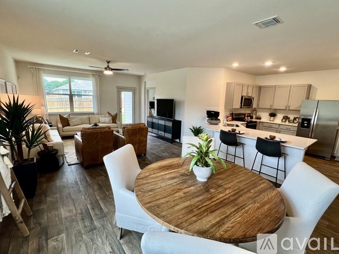 A modern kitchen with a wooden table and white chairs.