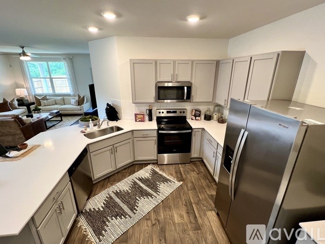 A kitchen with stainless steel appliances and wooden flooring.