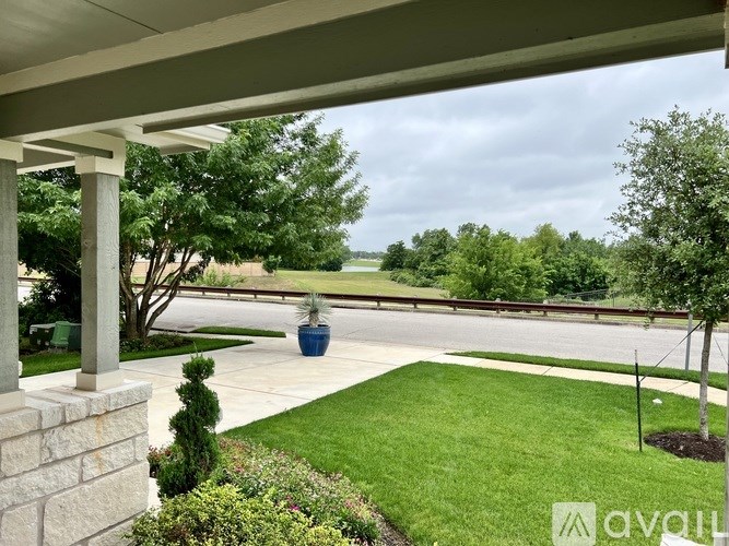 A porch with a view of a green lawn and trees.