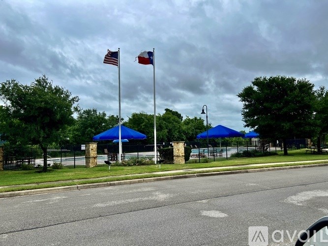 A street view with two flags on poles and blue canopies.