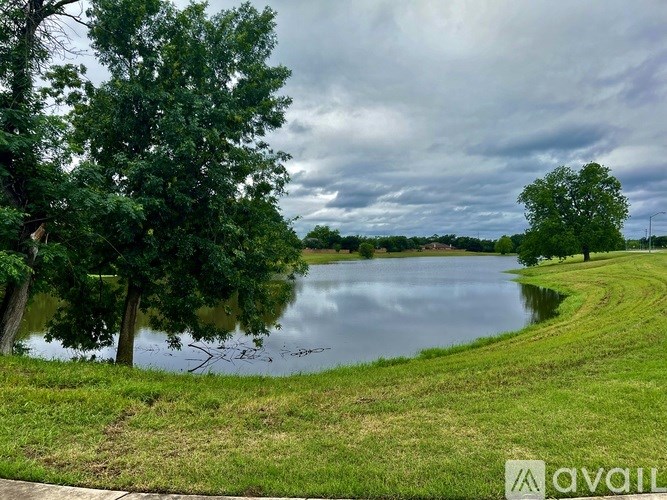 A lake surrounded by greenery and trees under a cloudy sky.