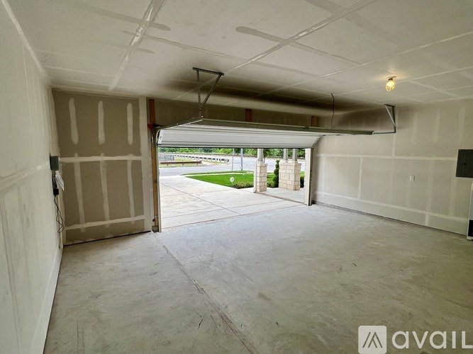 A spacious garage with a door open to a driveway.