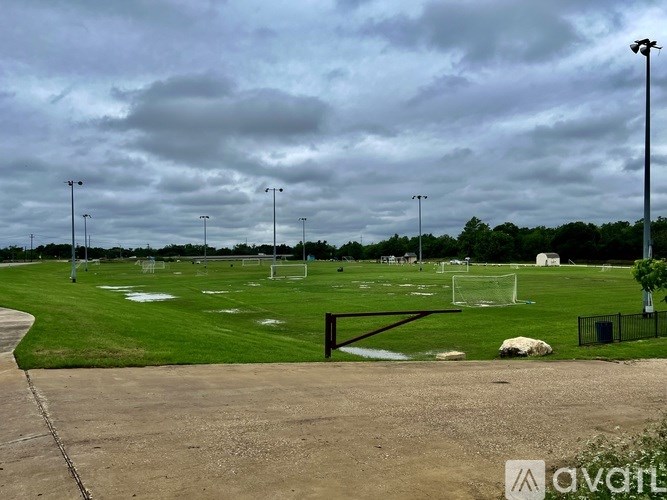 A cloudy day at the park with a soccer field and goal post.