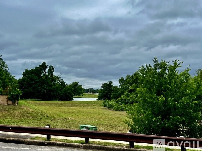 A green sign with the word "cyclist" on a fence in front of a grassy field.