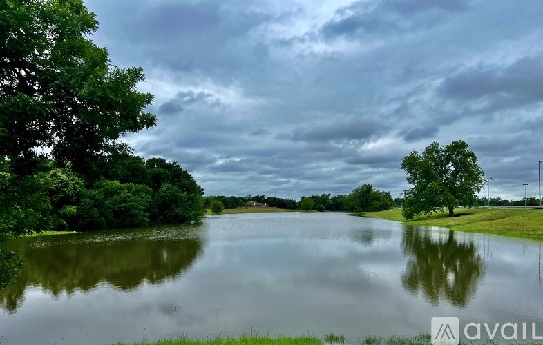 A calm lake surrounded by lush greenery under a cloudy sky.