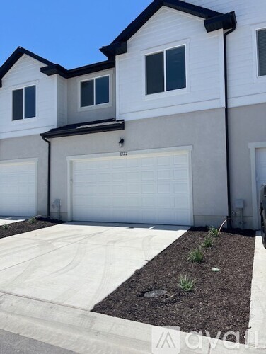 A white garage door is on the right side of a two-story house.