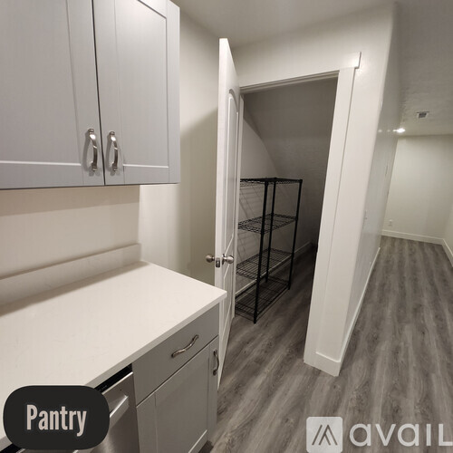 A pantry with white cabinets and a doorway leading to another room.