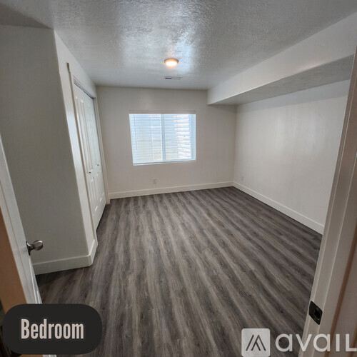 A bedroom with a grey carpet and a window with blinds.