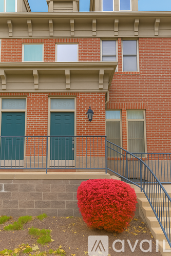 A red flowering shrub sits in front of a brick building.
