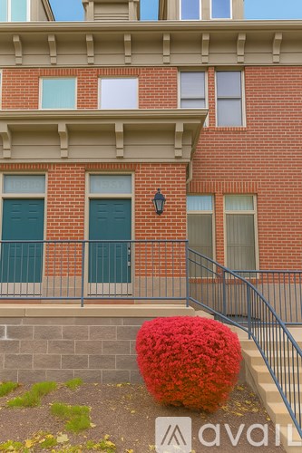 A red flowering shrub sits in front of a brick building.